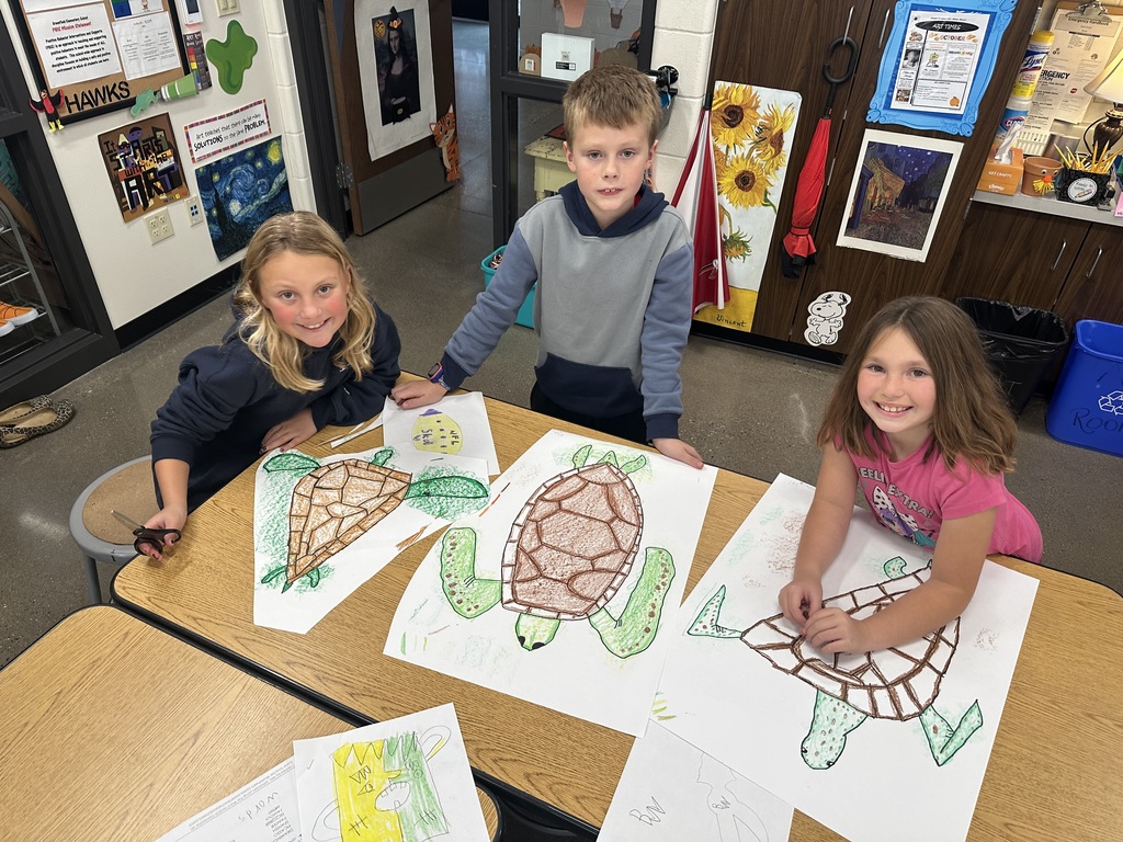 Three students in the art room with their projects.