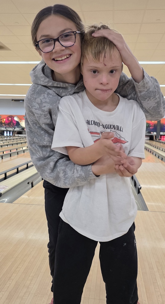 Two students smiling with bowling lanes behind them.