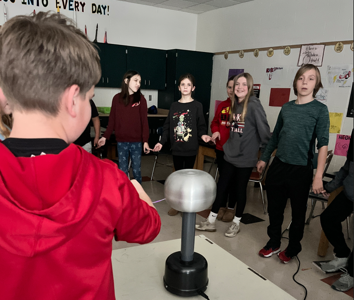 6th grade students holding hands in science class.
