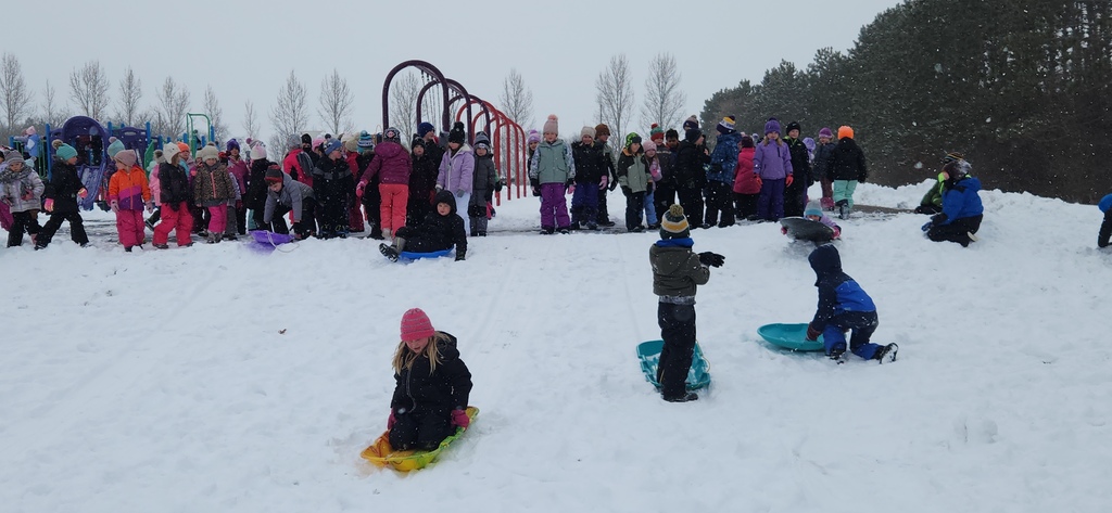 Students by playground equipment on sleds.