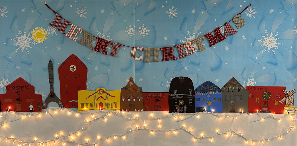 Artwork on a bulletin board with Christmas lights.