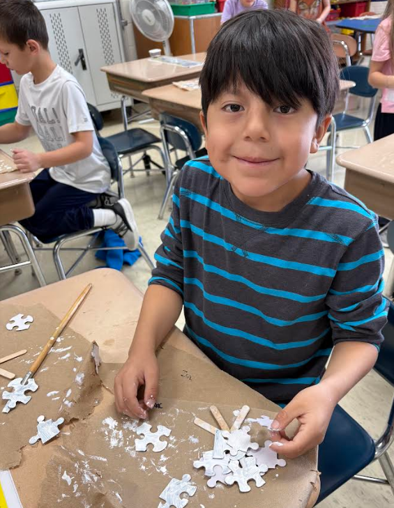 Child with puzzle pieces and paintbrush.