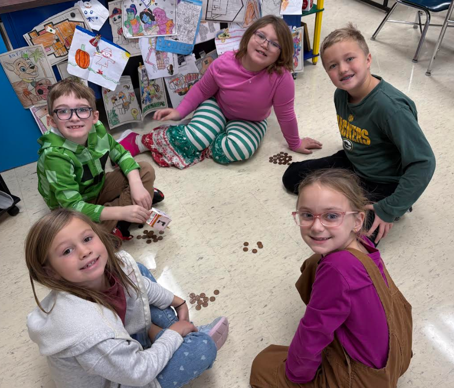 Smiling group of students playing a dreidel game.