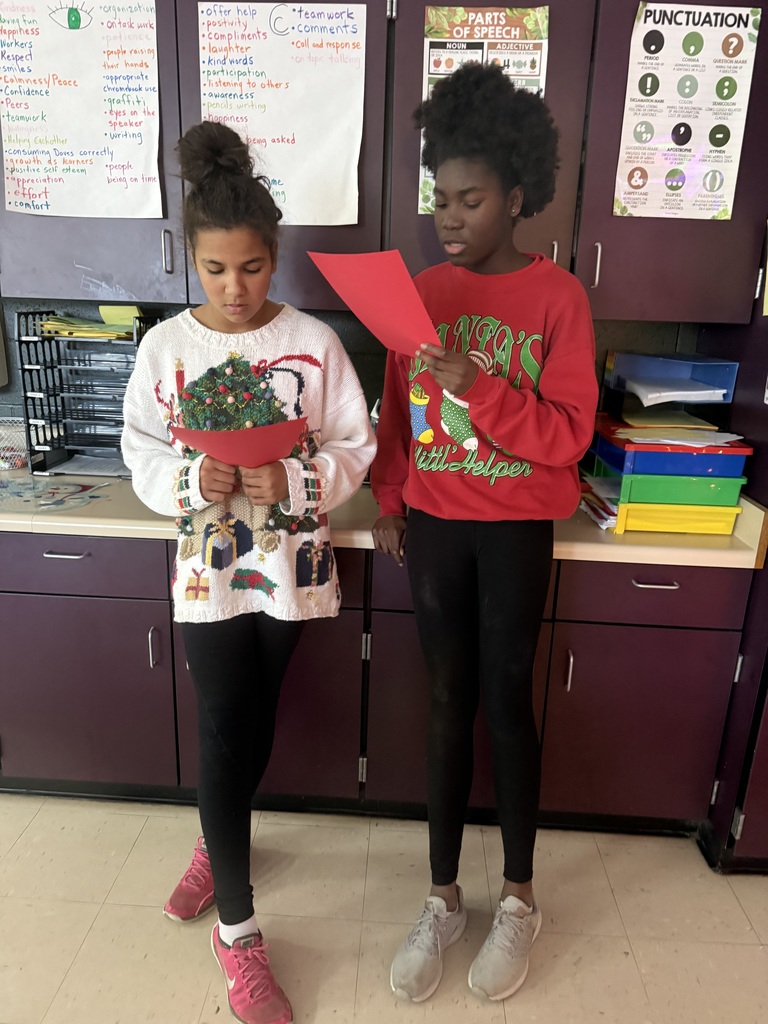 Two students standing reading to eachother.