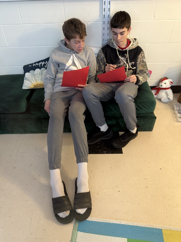 Two boys reading to eachother on the floor.