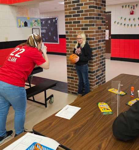 Studnet posing with a basketball while getting a picture taken.