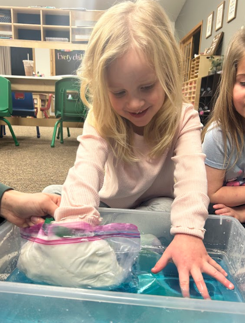 Student smiling with hands in the water.