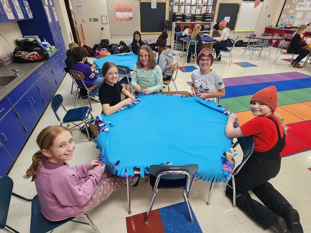 Group picture of students at desks working on blankets.