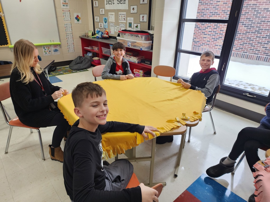 Students and teacher tying a blanket