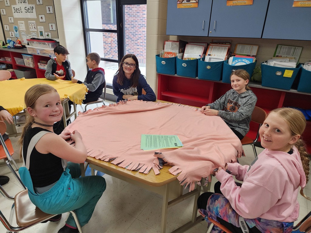 Group of smiling students making a blanket.