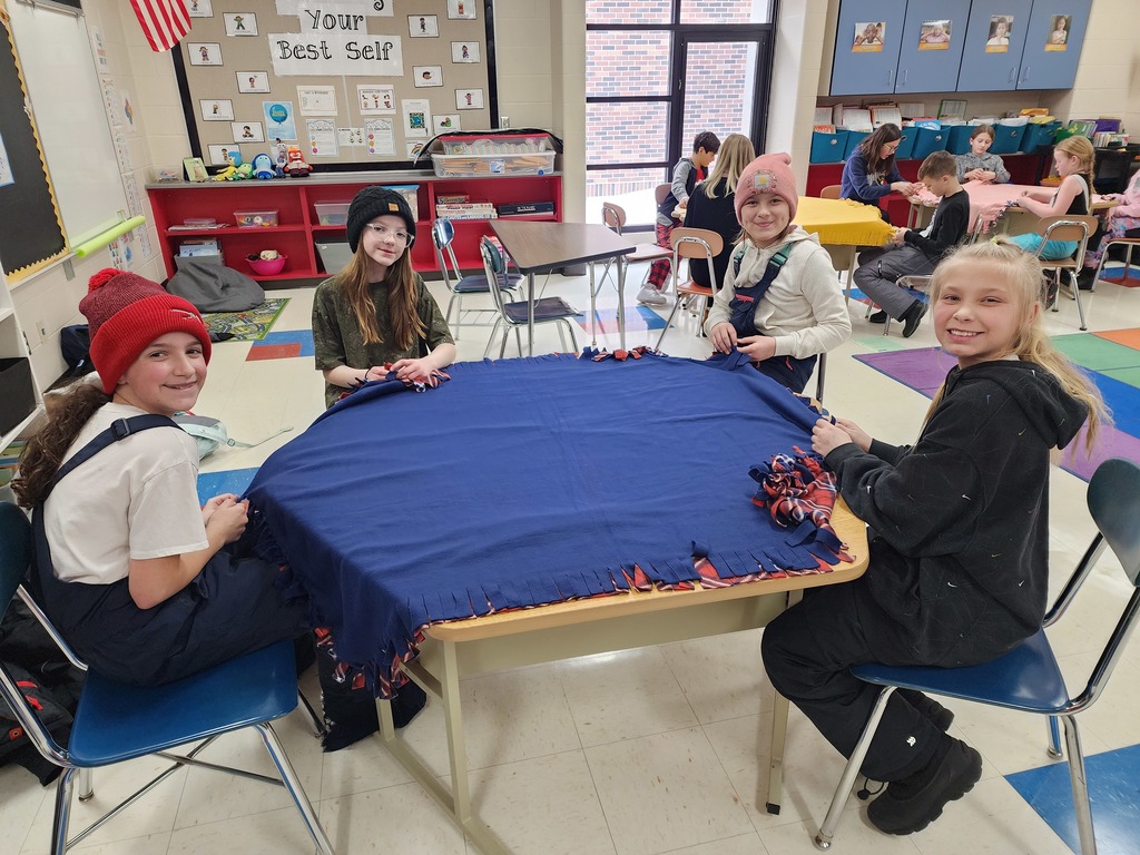 Students smiling and making a tie blanket.