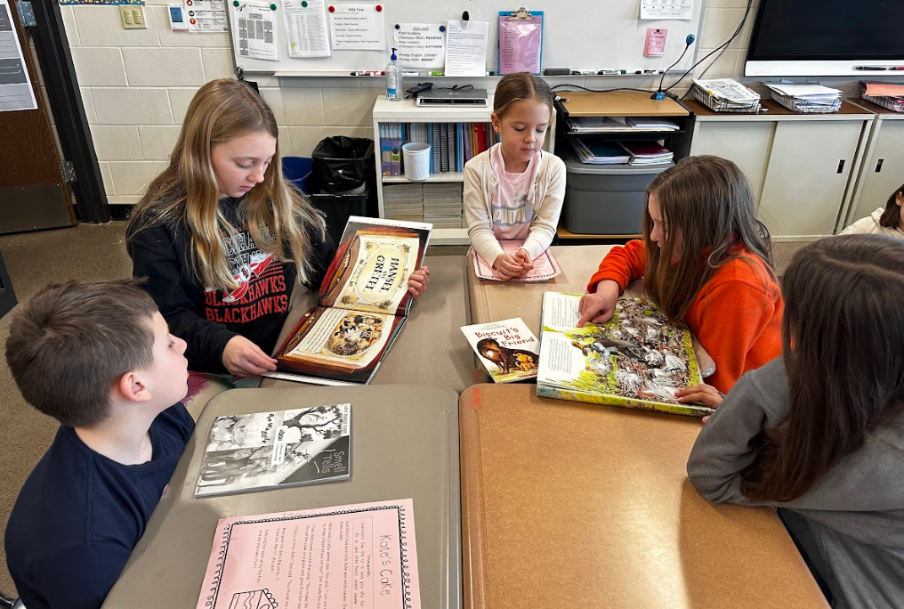 Group of students reading around desks.