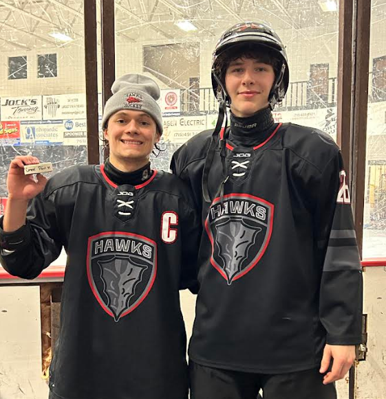 Hockey players smiling with a puck.