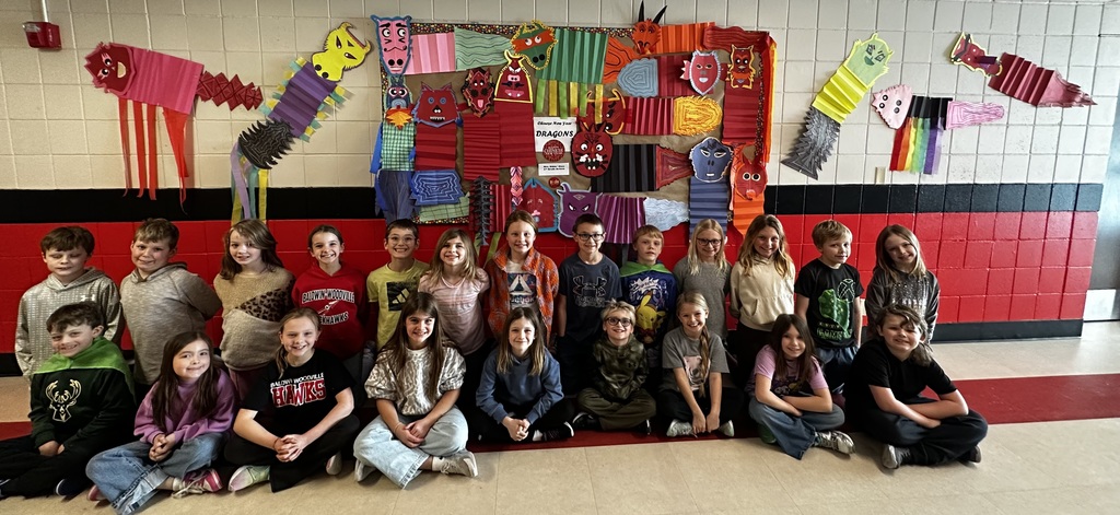 Students sitting in the hallway by their art projects.