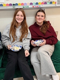 Two students smiling with bowls of ice cream.