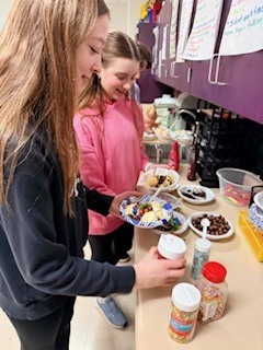 Students smiling and making their bowl of ice cream.