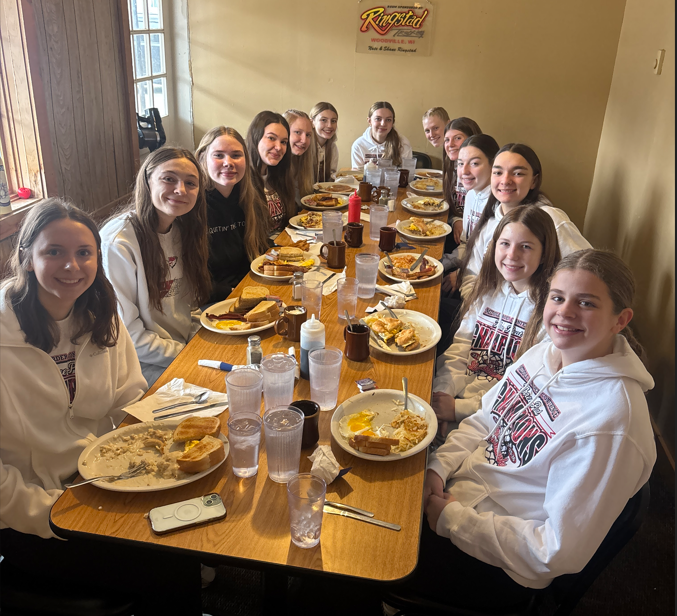 Varsity Girls Basketball team at the table eating breakfast.