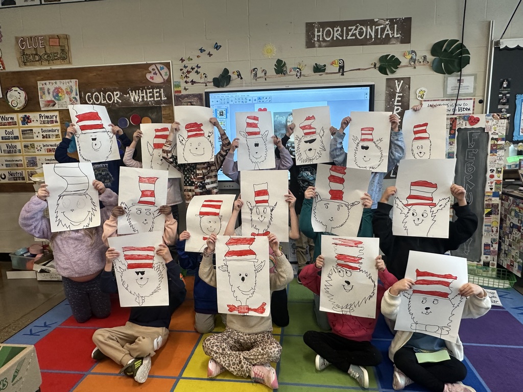 Students holding up their Cat in the Hat drawings.