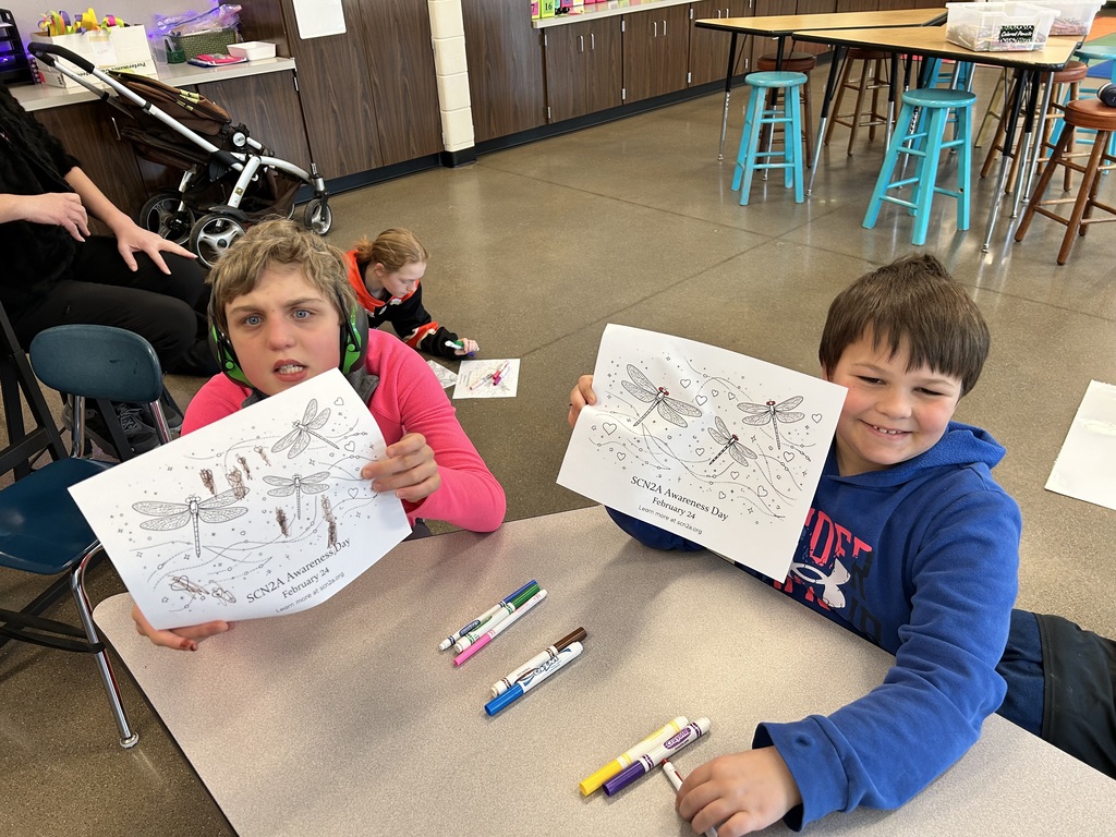 Two students smiling with their artwork.