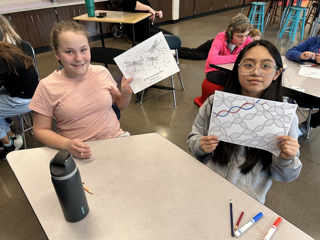 Students at their desk smiling.