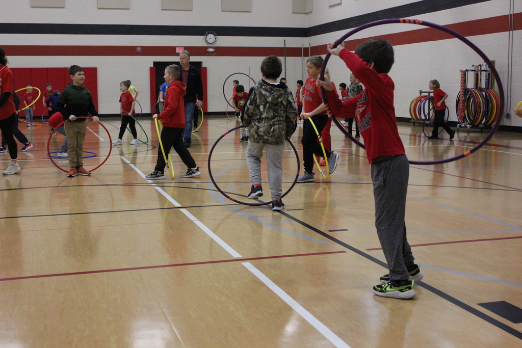 Younger students in the gym with their hula hoops.