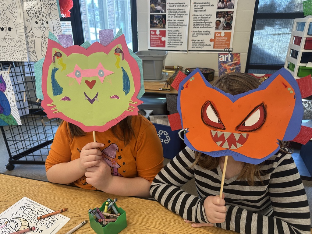 Students holding up a dragon mask in front of their face.