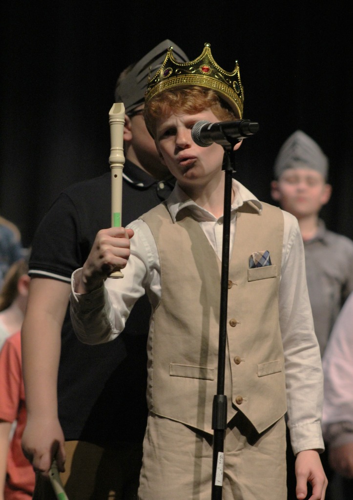 A boy dressed in a crown with his recorder.