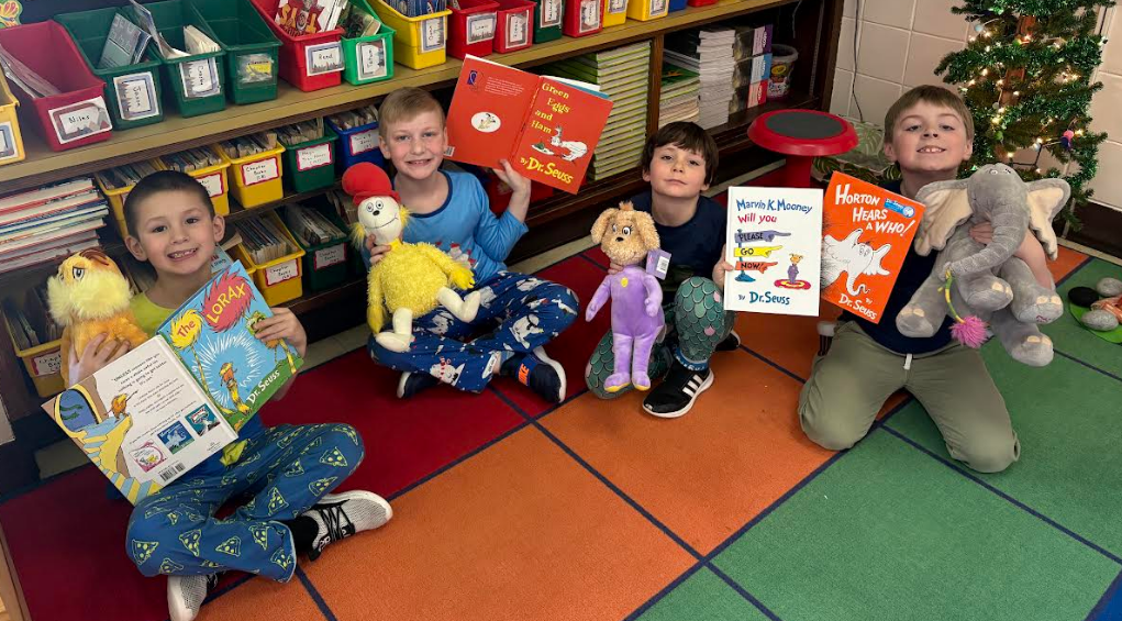 Four students sitting and reading with Dr. Seuss stuffed animals that match their books.