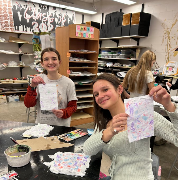 Two students smiling with their marbled paper.