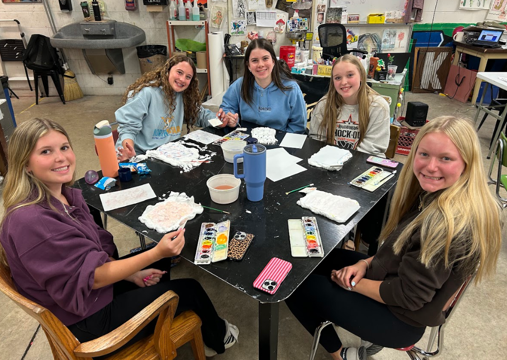 Five students at the art desk working on a project.