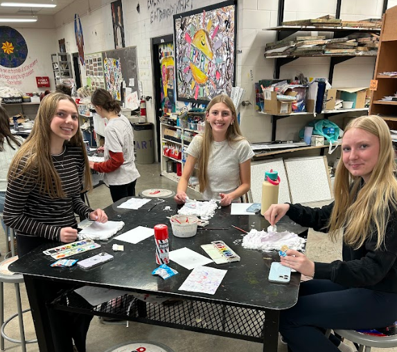 Three students smiling at their table.