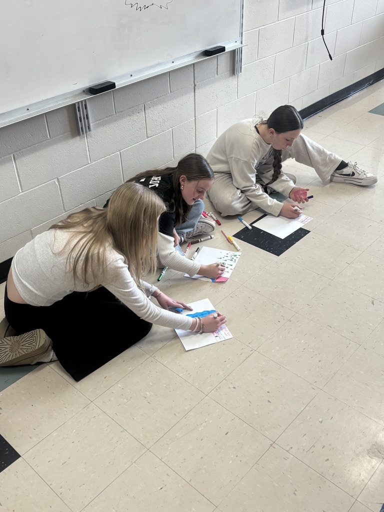 Students sitting of the floor working on their projects.