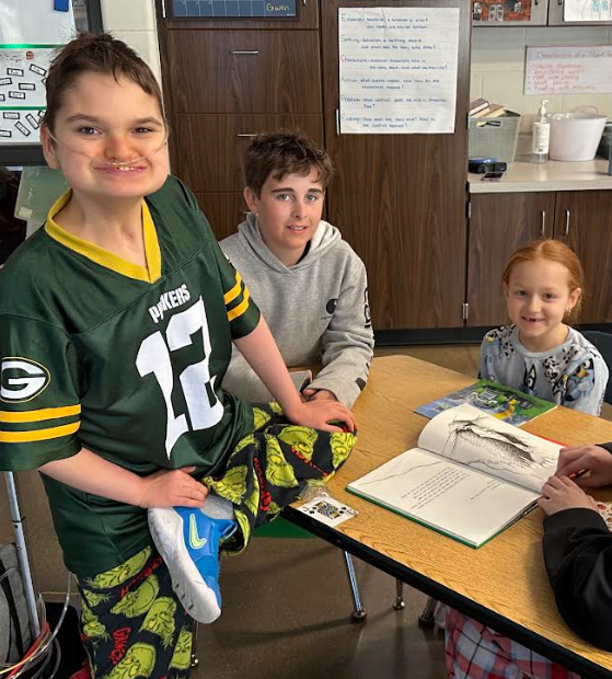 Three students pause from reading to give the camera a smile.