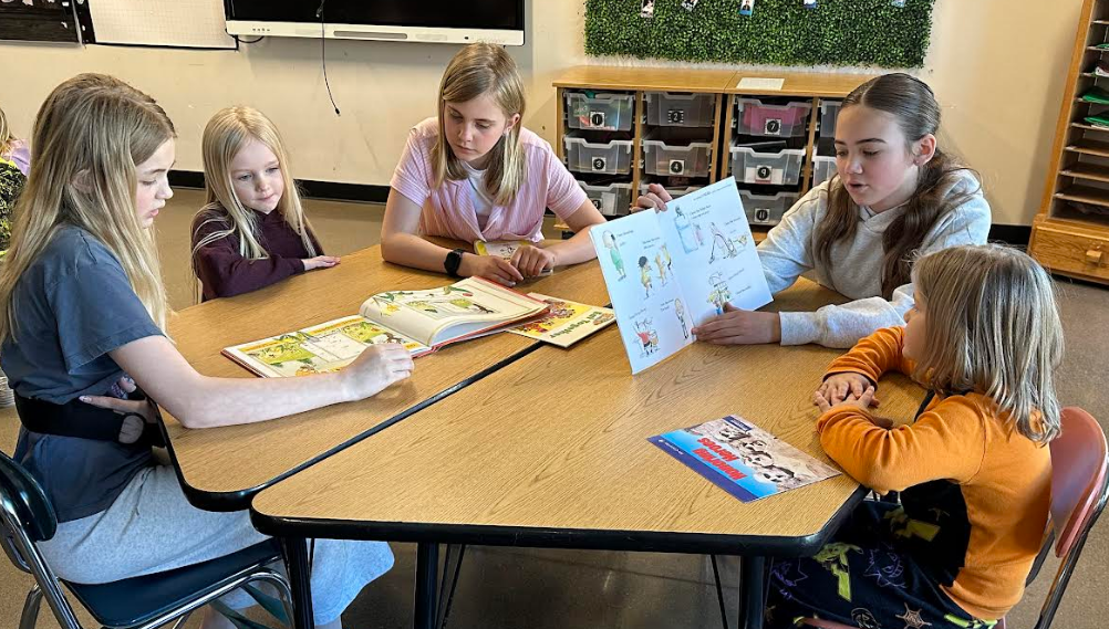 A larger group of students sitting at a table reading.