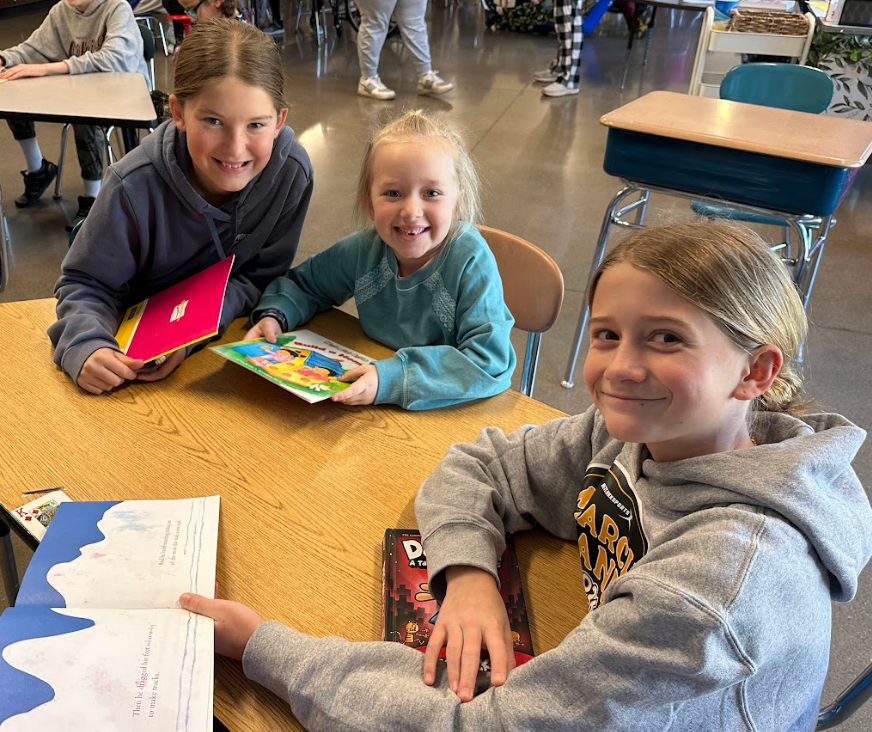 Three girls reading at their table.