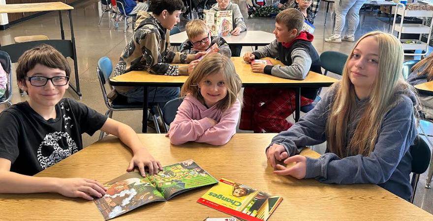 Students smiling at a table together with books in front of them.