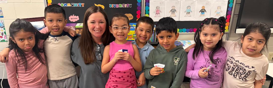 A group of students with their teacher. Most are smiling and one with a sad face.