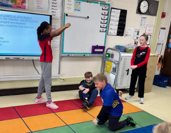 Two students on the group and two standing acting out the play.
