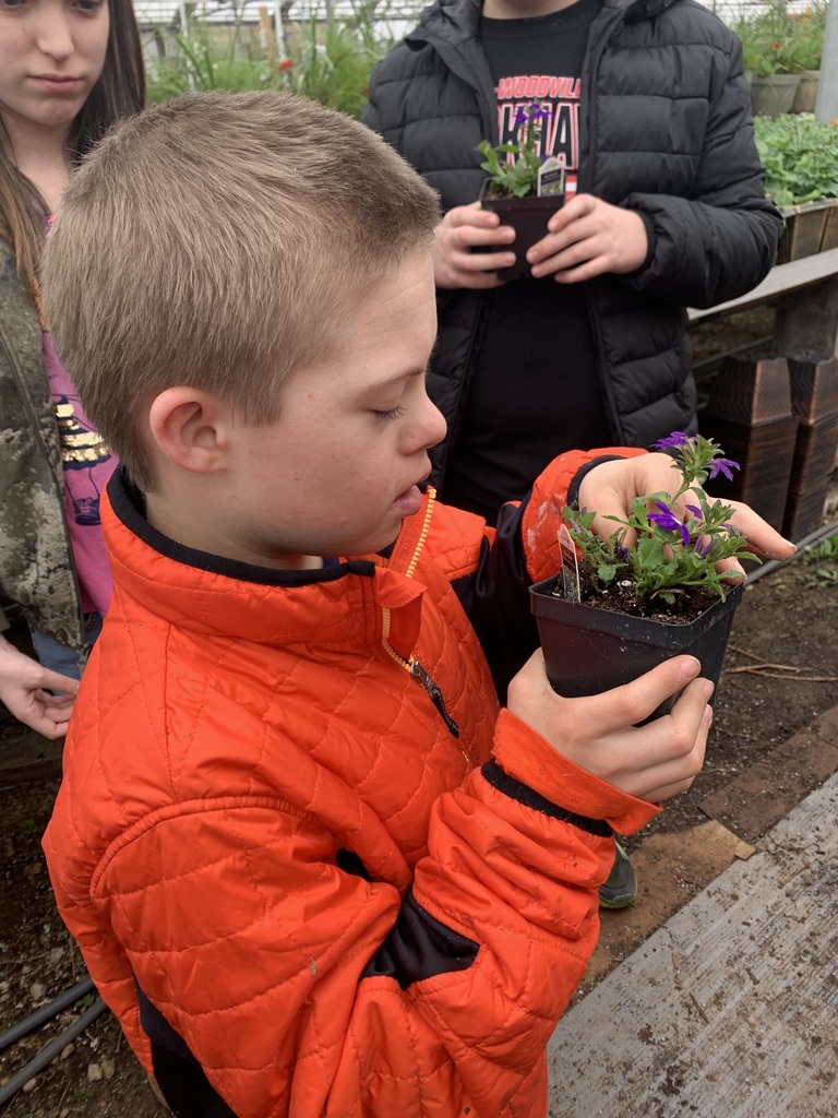 Another student holding and looking at his flower.