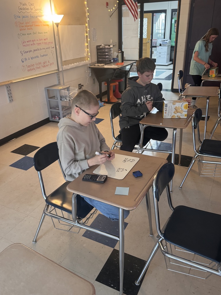 Two students sitting at their desks measuring boxes.