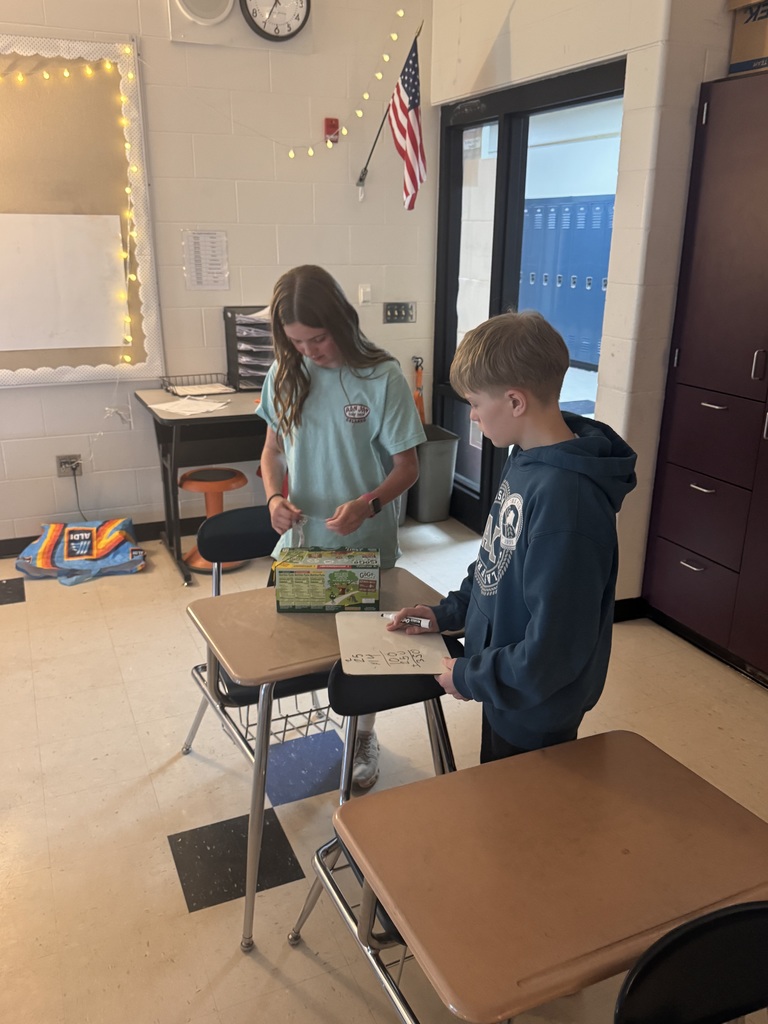 Two students standing by their desk measuring a box.