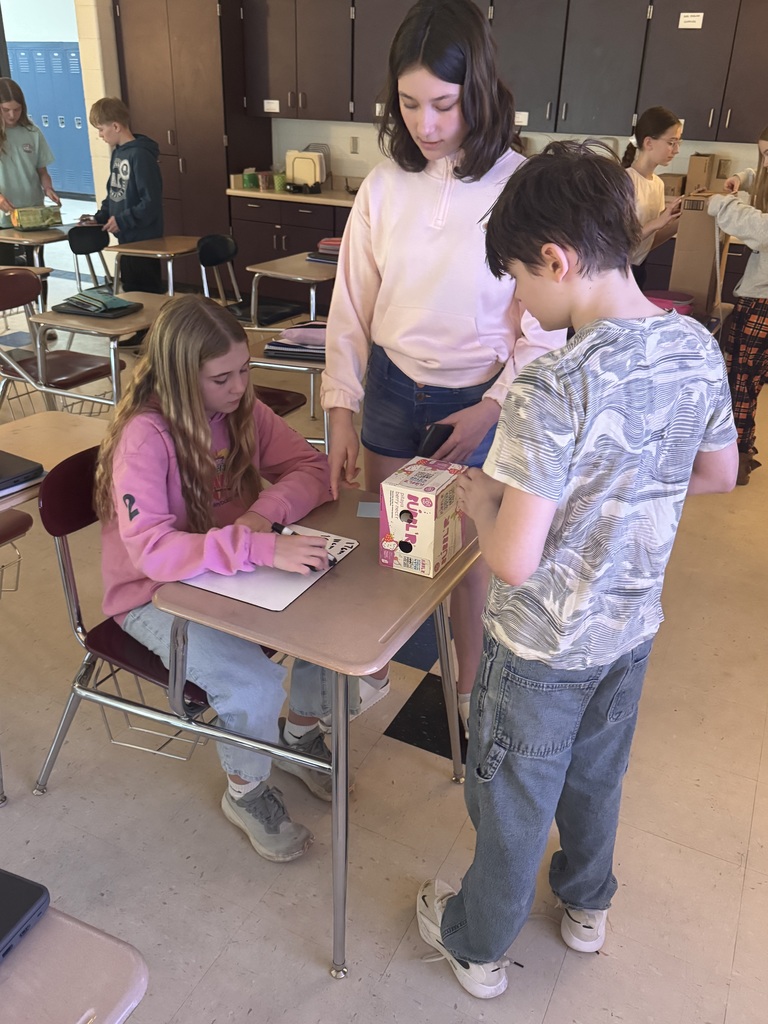 Students standing/sitting around a desk measuring.