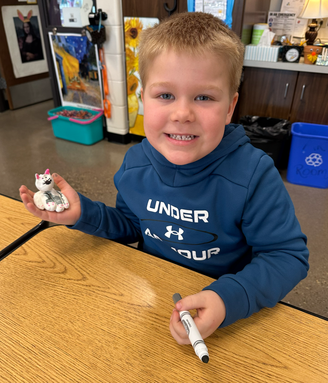 A little boy smiling with the cat he made.