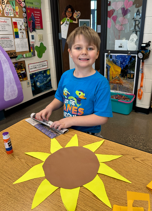 A student smiling while working on their sunflower.