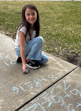 Little girl playing with chalk on the sidewalk.