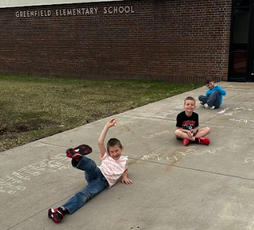 Three boys sitting on the sidewalk working on math facts.
