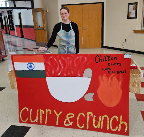 A student smiling with her "food truck"  CURRY AND CRUNCH