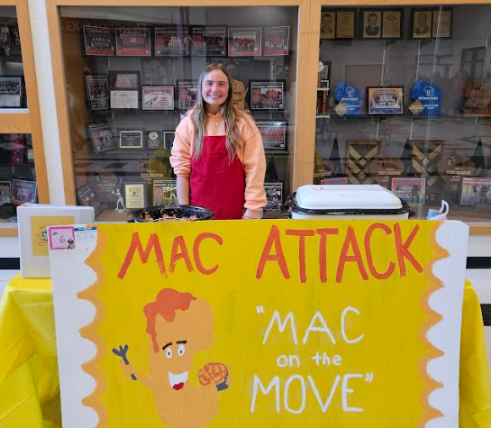 A student smiling with her "food truck" MAC ATTACK.