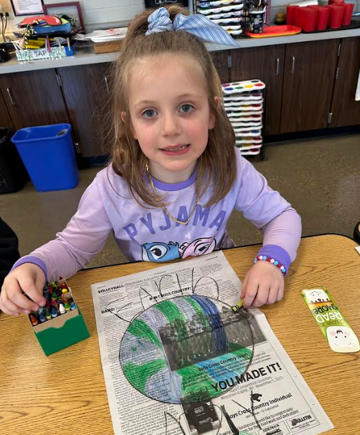 A girl coloring on newspaper.