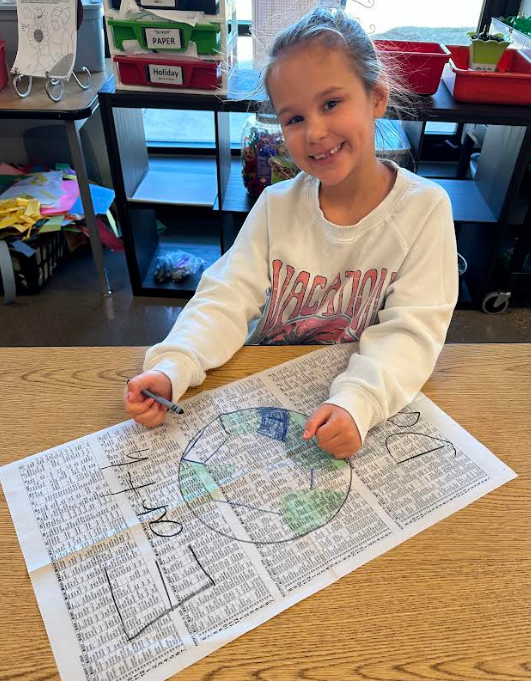 A little girl smiling with a crayon.